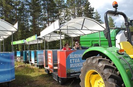 Tiedottaja Minna Kylälehtonen ja näyttelypäällikkö Jukka Isotalo istuvat messujunassa, joka kuljettaa näyttelyvieraita ympäri 23 hehtaarin näyttelyaluetta.