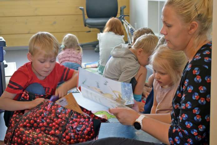 Venla Lehtimäki kuuntelee Heidi Vainion kertomaa satua Auran Pilke Kurjessa. Väinö Lehtimäki etsii jotain luettavaa kirjakassista.