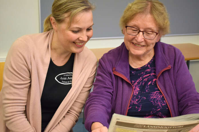Heidi Ahlgren ja Taimi Heikkilä lukevat lehteä ja keskustelevat sitten jutuista ryhmän kanssa ruotsiksi. Kuva: Tuomas Honkasalo