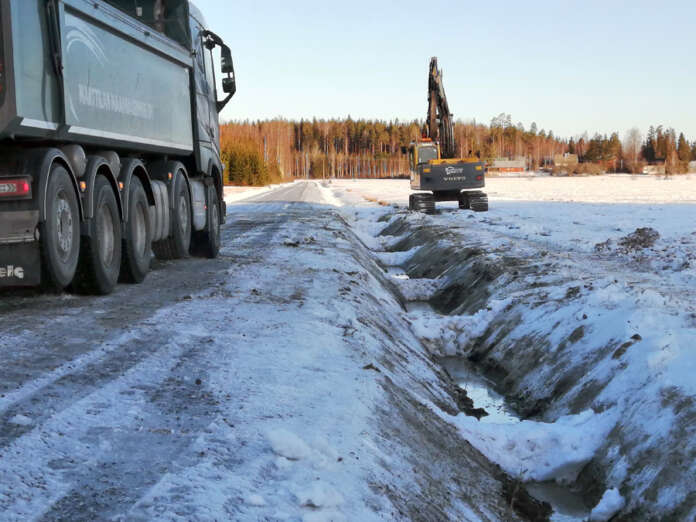 Öljyistä lunta ja maata poistettiin Rasuntieltä perjantaina aamupäivällä. Ojaan tehdyt lumipaakut muodostavat sulkuja ja niistä pystytään seuraamaan, muodostuuko öljyä vielä ojaveden pinnalle. Kuva: Simo Päivärinta.