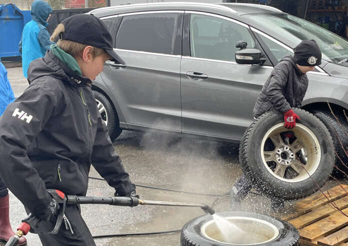 Wiljam Sipilä, 13, pesi renkaita kovalla tohinalla painepesurin kanssa ja Samuel Toivonen, 11, koitti väistellä renkaan kanssa roiskeita. Kuva: Tuomas Honkasalo