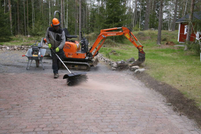 Kun kivetys on valmis, kivisaumat täytetään hiekalla ja kivet harjataan puhtaaksi. Pertti Leppäkoski harjan varressa.