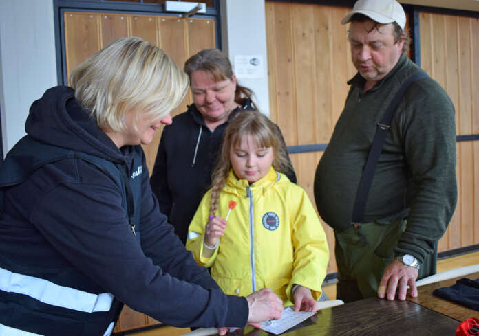 Kosken kunnan ravinto- ja puhdistuspalveluohjaaja Kirsi Jokela laittoi kunnantalon valtuustosalissa leiman Aino Nurmisen, 9, leimapassiin. Niina ja Marko Nurminen olivat tyytyväisiä Koskituksen tarjontaan. Kuva: Tuomas Honkasalo